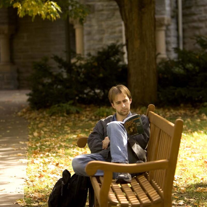 Student sitting on a bench reading a book